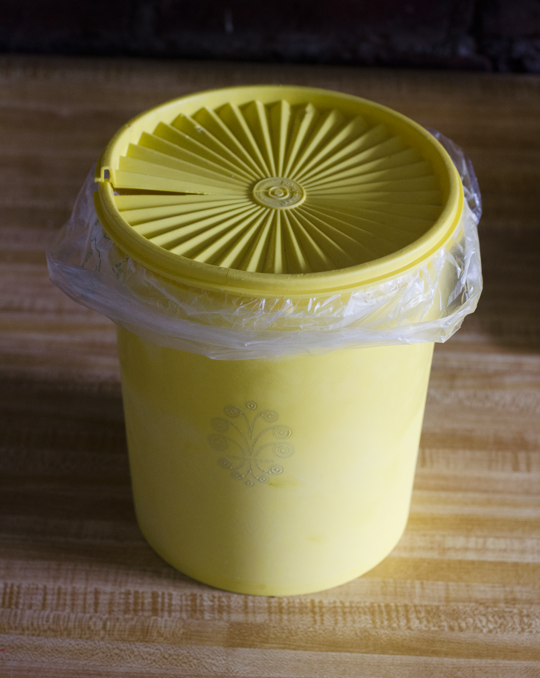 Vintage yellow Tupperware canister as compost bin